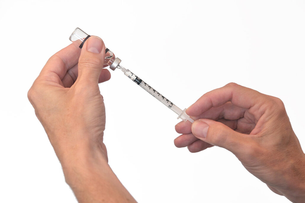 Hands holding an allergy shot vial