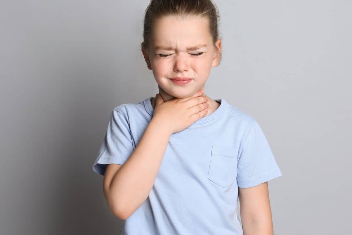 A child experiencing throat discomfort, symbolizing asthma challenges and the importance of proper treatment.