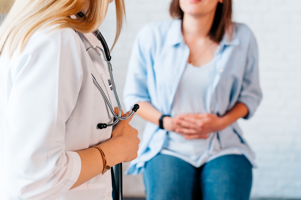 Doctor consulting a woman with abdominal discomfort, discussing GERD diagnosis and prevention of esophageal damage.