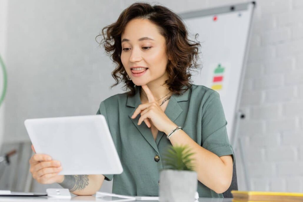 Woman practicing voice therapy techniques using a tablet, demonstrating personalized vocal exercises during an online session.