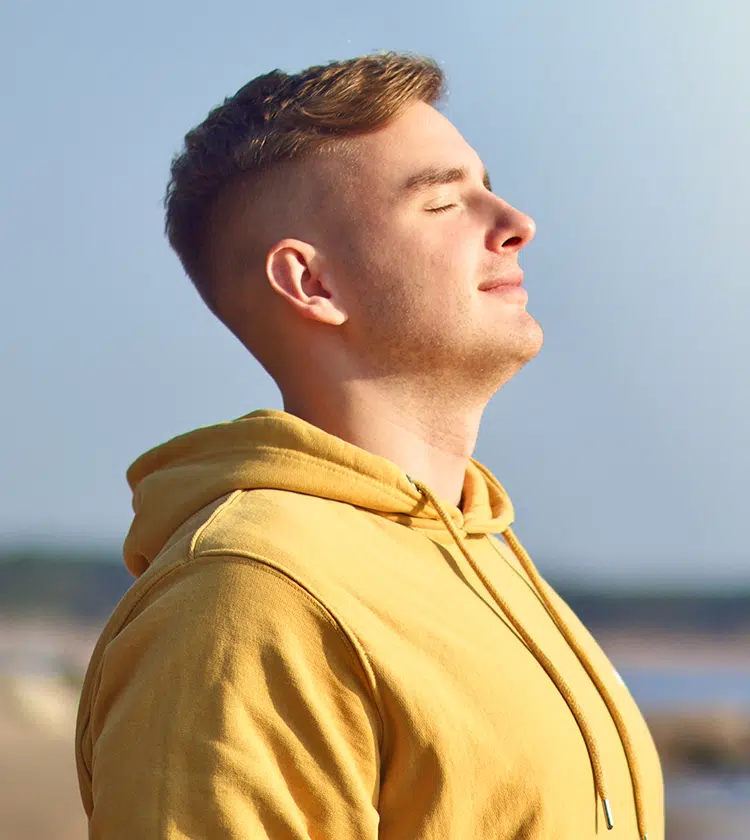 Man in yellow hoodie breathing deeply with closed eyes, representing improved breathing after septum treatment.