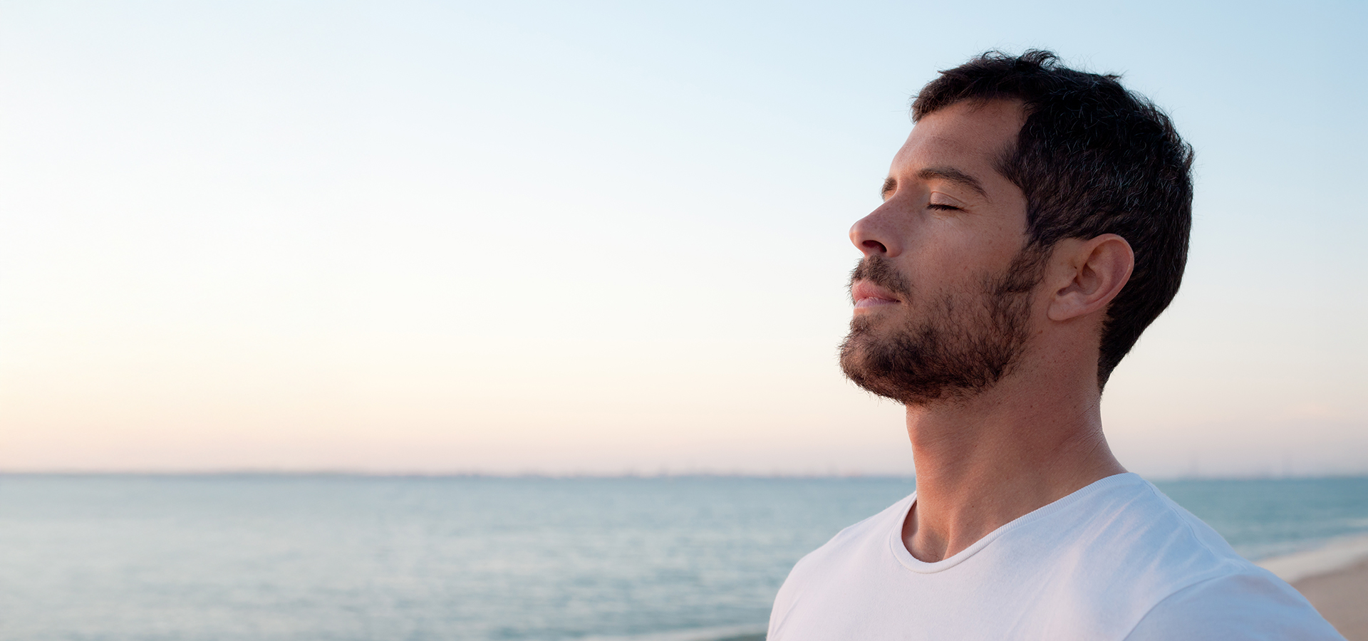 Man standing by the sea with closed eyes, breathing calmly to represent relief from nasal congestion and blockage