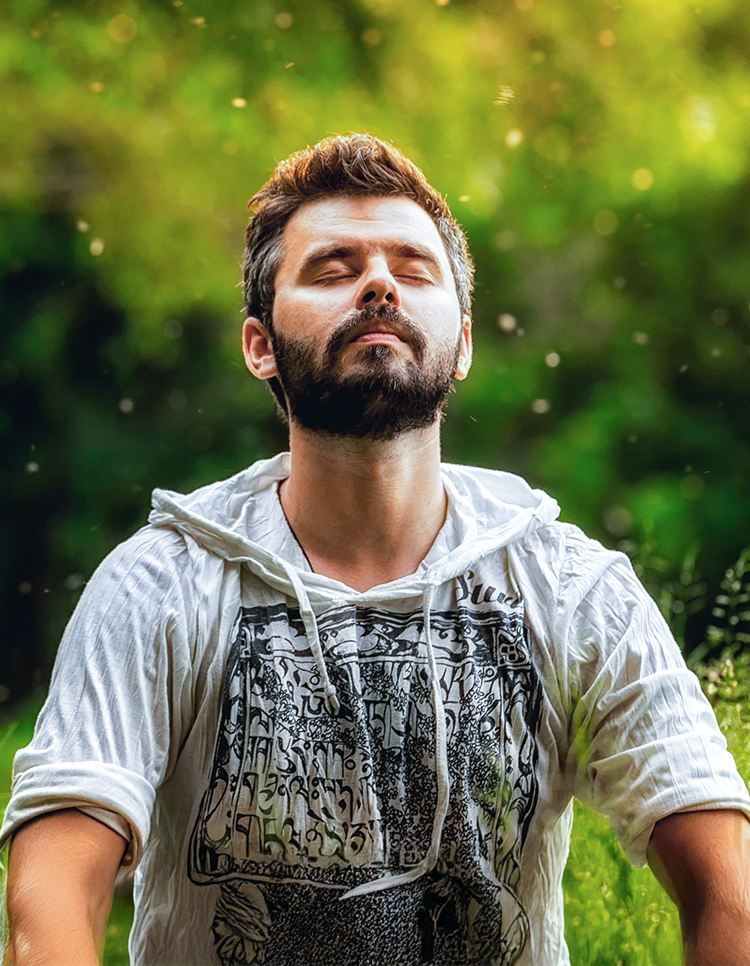Man breathing deeply outdoors with closed eyes, illustrating awareness of nasal congestion risk factors like allergies and colds.