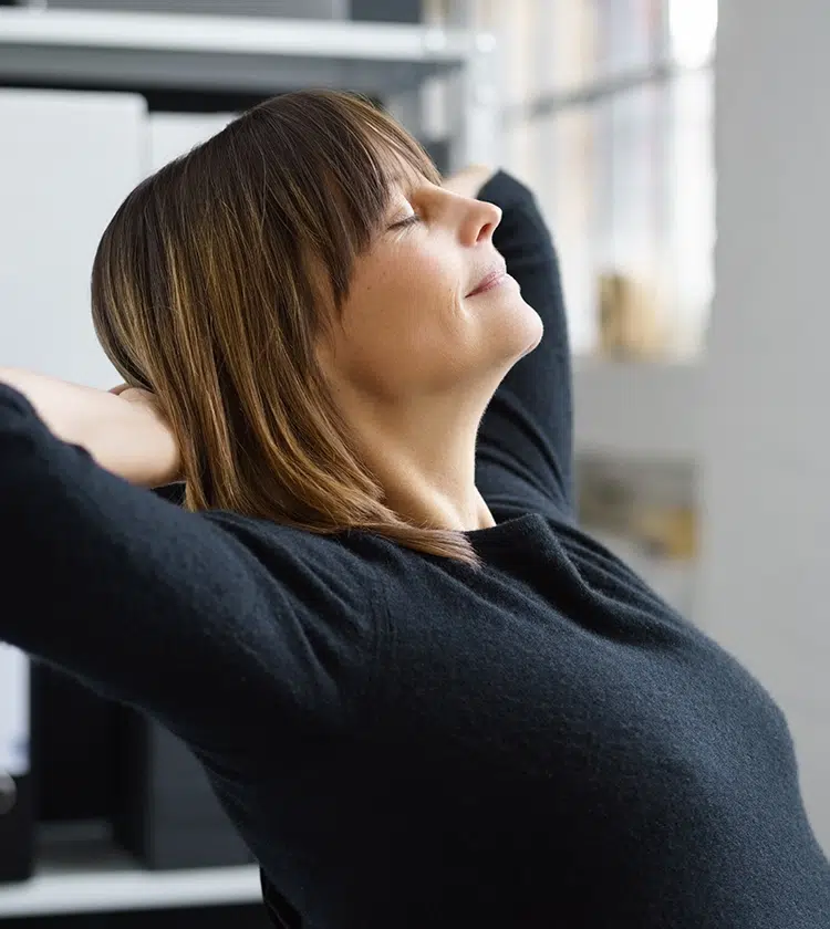 Content woman stretching with eyes closed, reflecting peace of mind after learning about neck mass risk factors and detection.