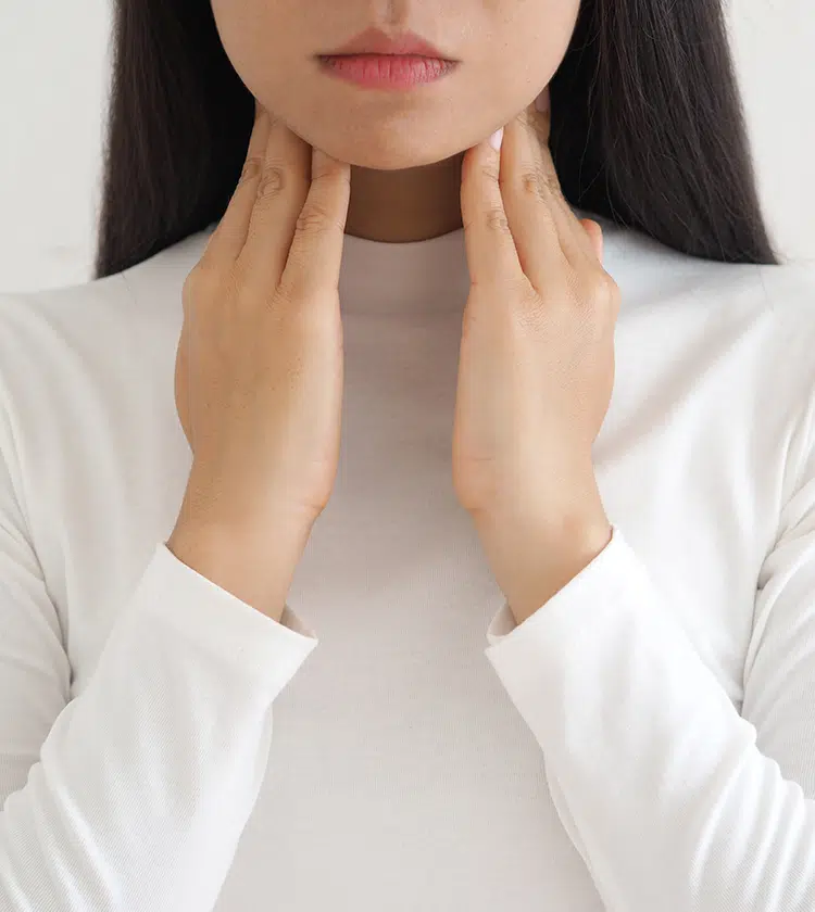 Woman touching throat with both hands, indicating throat discomfort from post-nasal drip symptoms like irritation.
