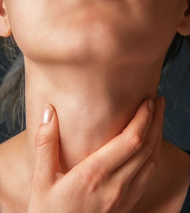 Close-up of person touching throat, highlighting symptoms of neck masses like swelling or discomfort.