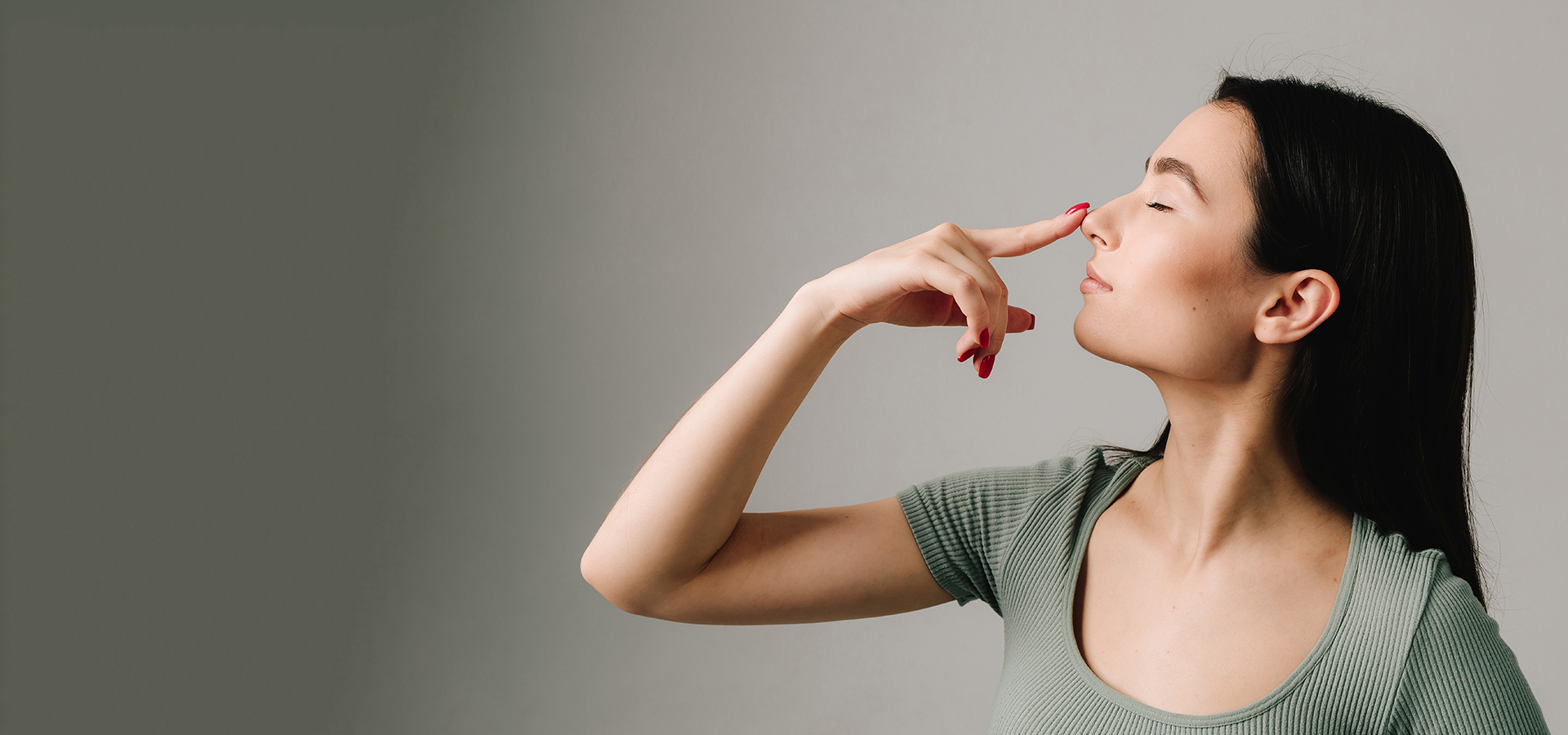 Woman touching her nose gently, symbolizing nasal concerns related to a deviated septum and its treatment.