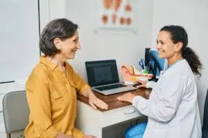 Smiling patient consulting with ENT doctor in medical office, discussing symptoms and treatment options during first visit.