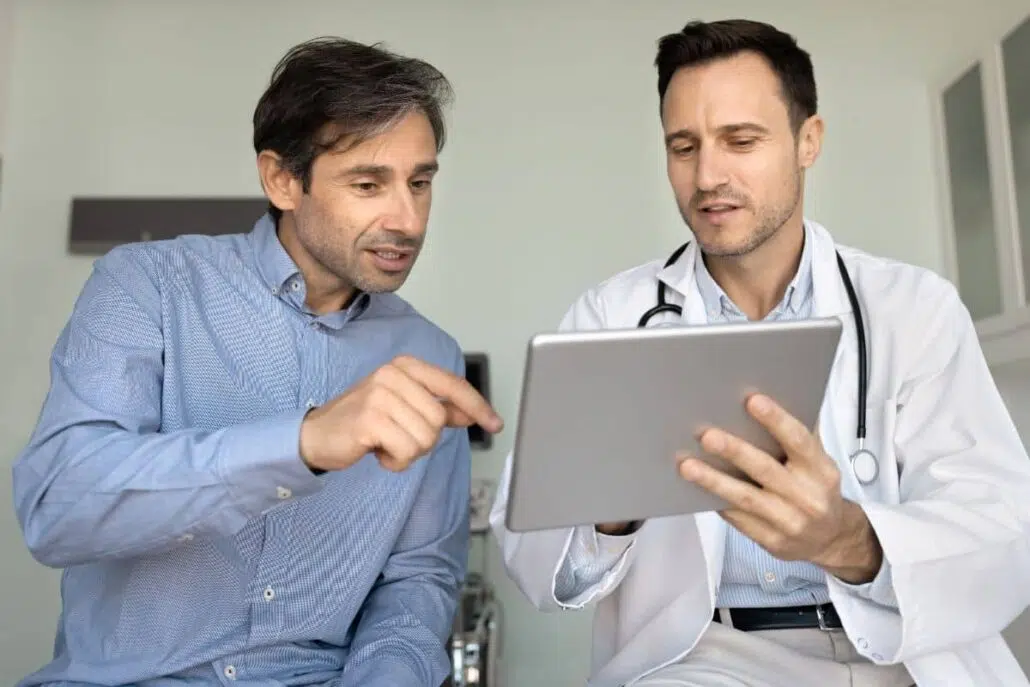 Patient and ENT specialist reviewing health concerns on tablet, discussing prepared questions during medical consultation.