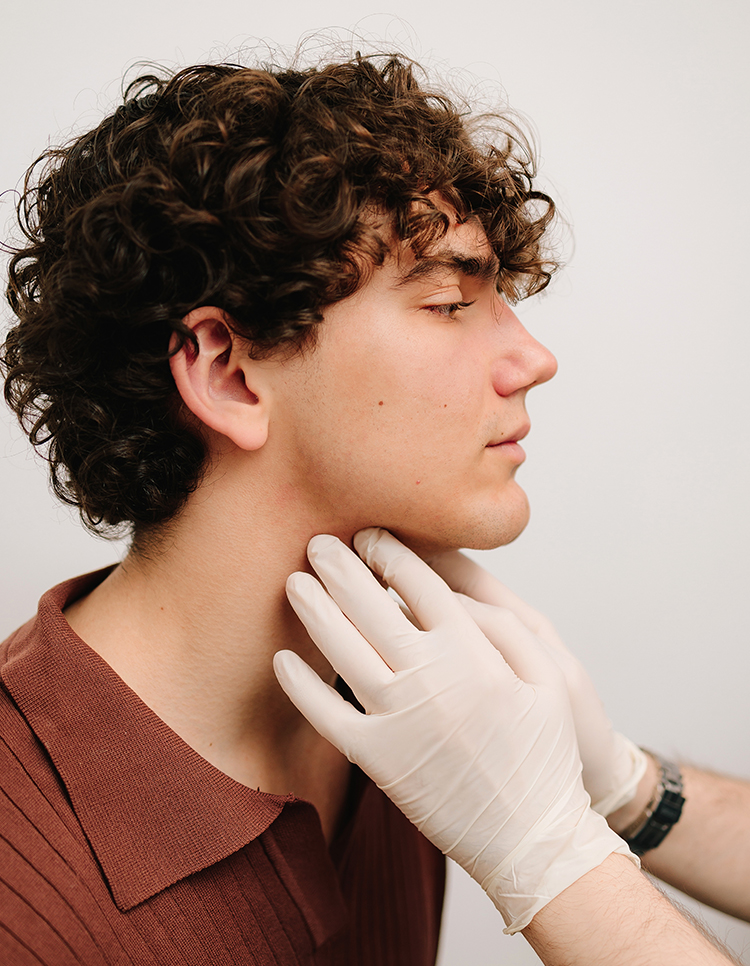 Healthcare professional examining young man’s neck for potential salivary gland mass linked to lifestyle risk factors
