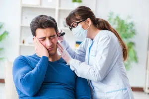 Female ENT doctor examining a male patient suffering from sudden ear pain in a clinical setting