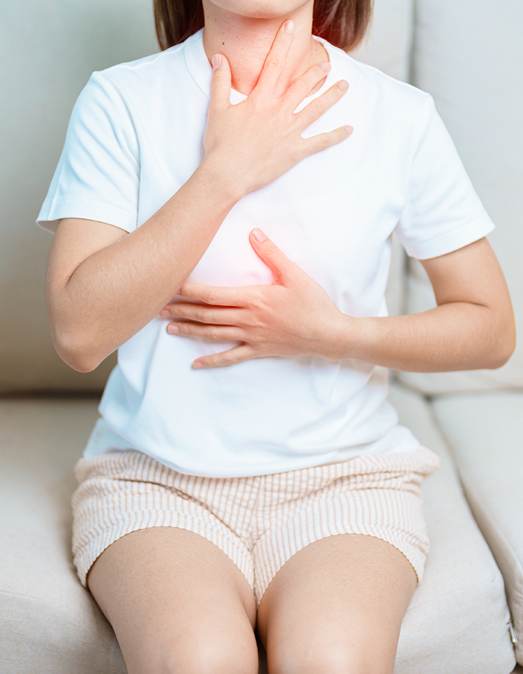 Woman holding her throat and chest, showing signs of laryngopharyngeal reflux affecting voice and throat