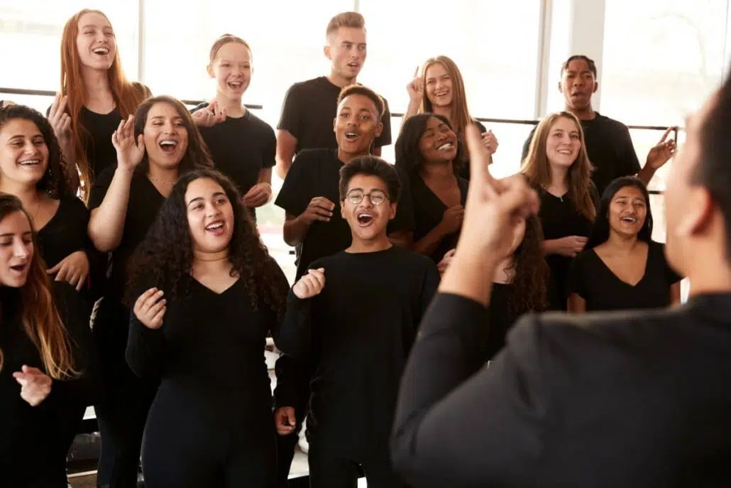 High school choir students singing under conductor’s lead.