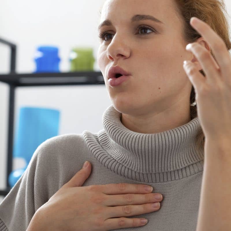 Female singer performing vocal exercise with hand on chest, illustrating vocal hygiene and ENT support for throat care.