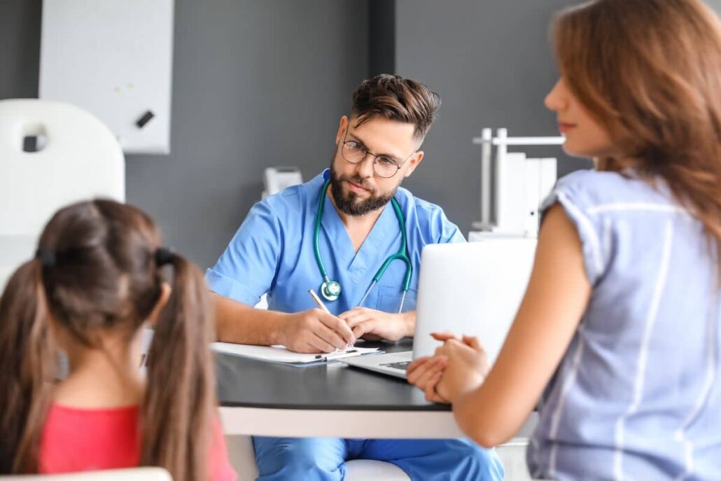 Physician advising mother and child on allergy test preparation steps during clinic visit to ensure reliable outcomes.