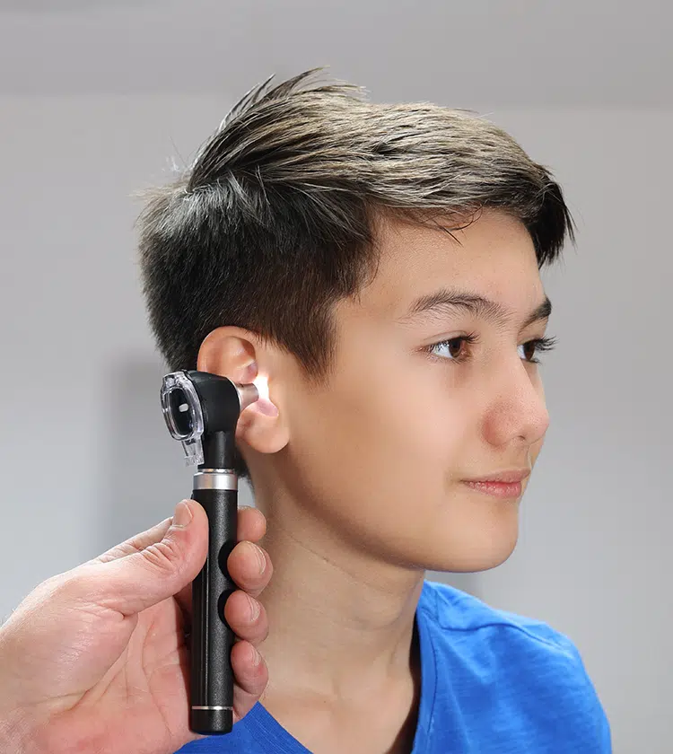 Child receiving ear examination with otoscope at urgent care clinic, highlighting treatment options for young patients