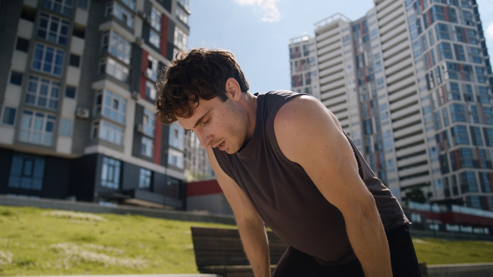 Man hunched over outdoors showing signs of exercise-induced anaphylaxis, a rare allergic