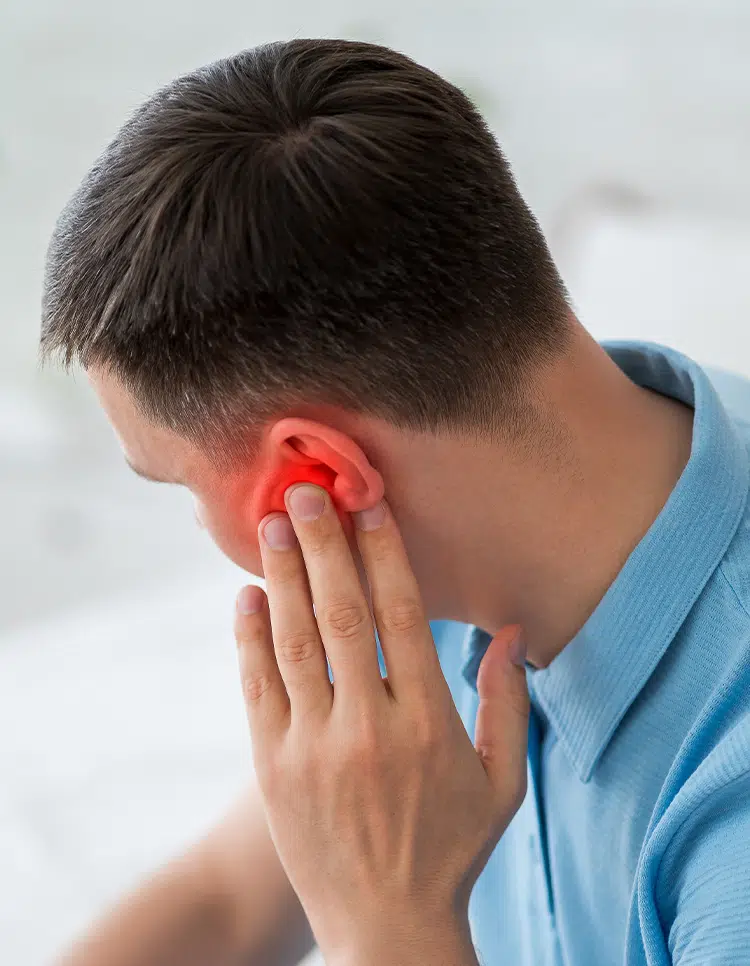 Man touching red-inflamed ear indicating pain, illustrating symptoms of a middle ear infection needing treatment