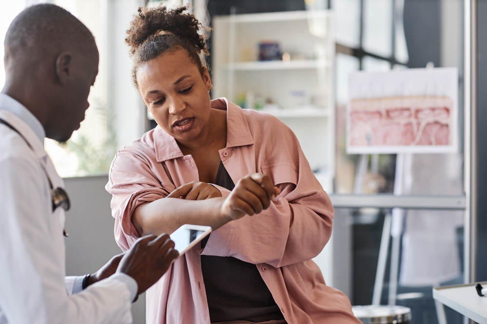 Doctor examining a woman's arm for signs of a severe allergic reaction in a clinical setting for urgent care.
