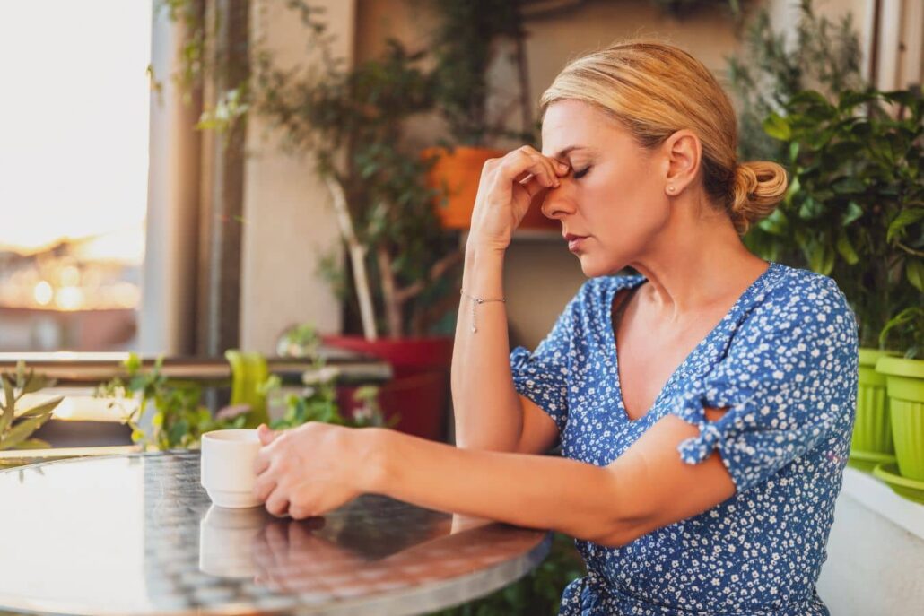 Woman pressing her nose in discomfort, representing summer sinus pressure, humidity, and mold-related allergies in Marlton.
