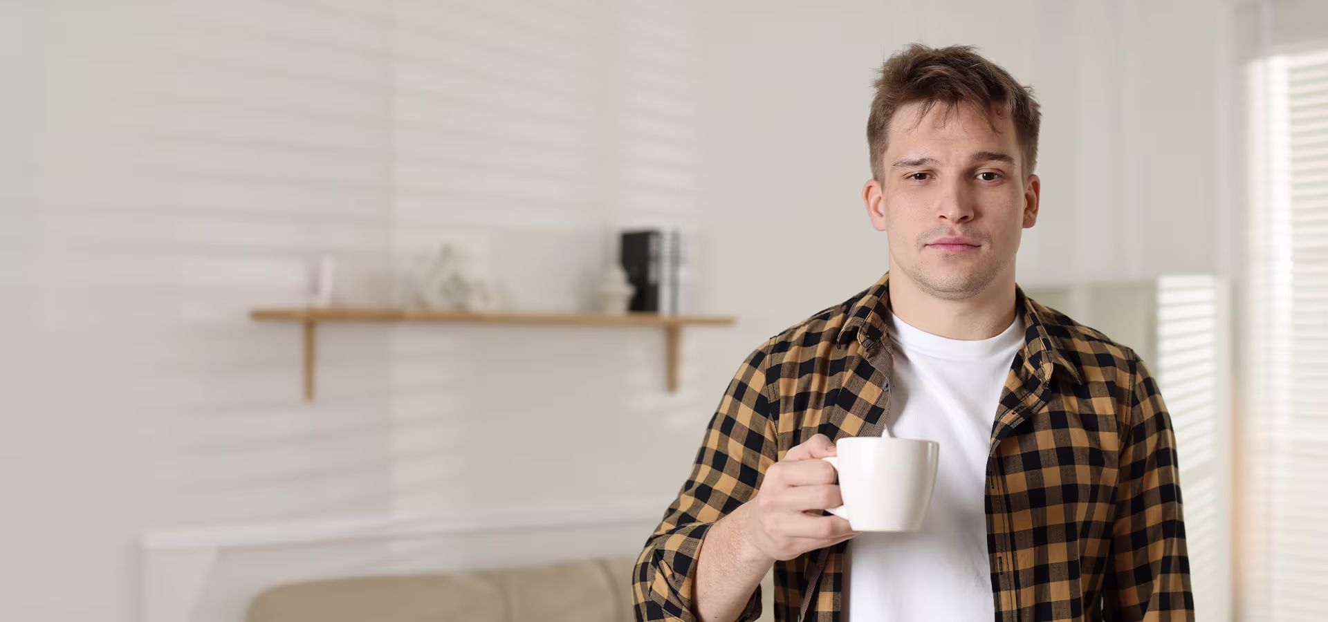Man holding coffee looking fatigued, representing excessive daytime sleepiness and central hypersomnolence disorders