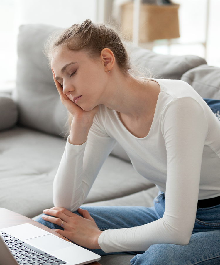 Woman feeling drowsy while using laptop, illustrating excessive daytime sleepiness and central hypersomnolence evaluation