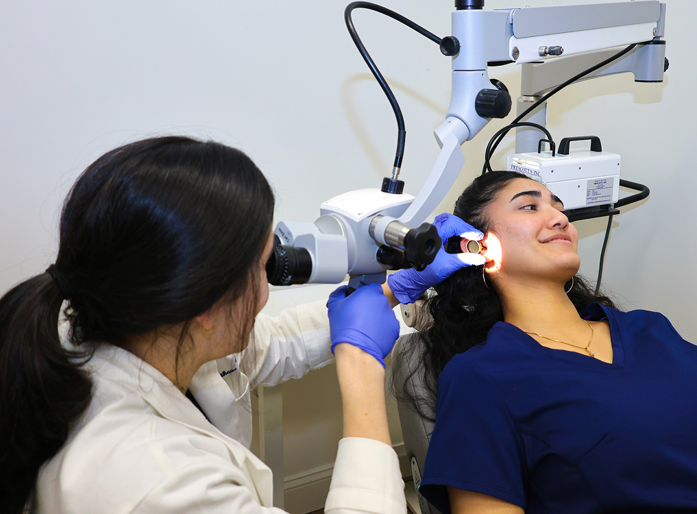 ENT specialist examining a patient’s ear with a microscope during an evaluation for hearing loss in a clinic.