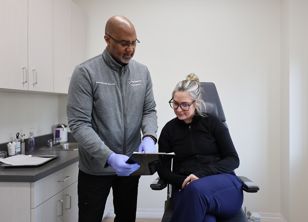Doctor reviewing tablet with patient in clinic while discussing sinus infection symptoms like congestion and facial pain