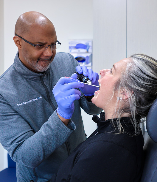 Specialist examining patient’s throat with medical scope to assess vocal cords and diagnose voice disorders in clinic