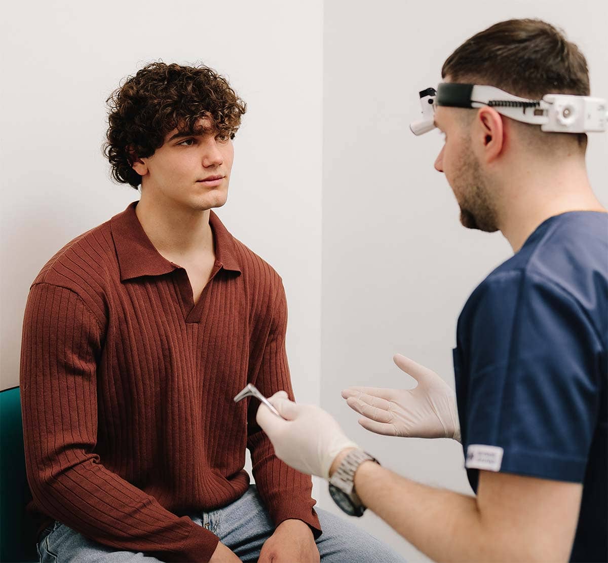 Doctor explaining types of salivary gland masses to a patient during a consultation using an anatomical diagram.