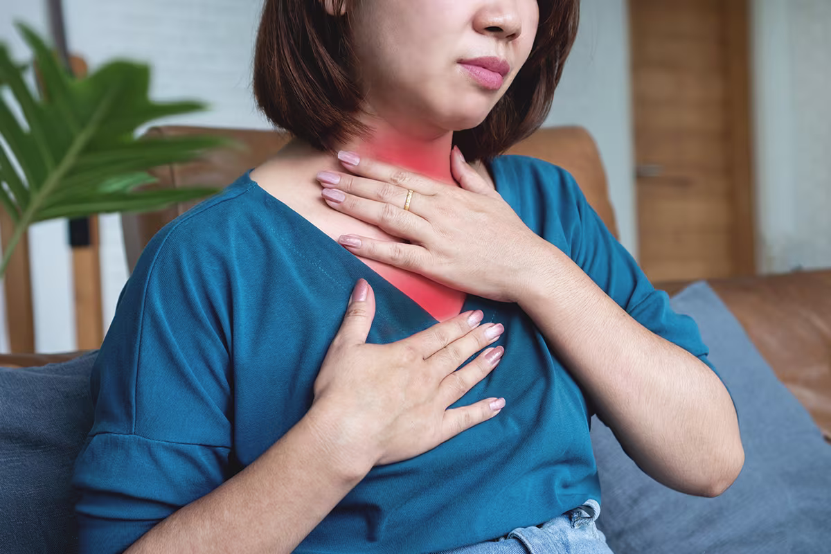 Person experiencing throat discomfort from laryngopharyngeal reflux with highlighted irritation in neck and chest.