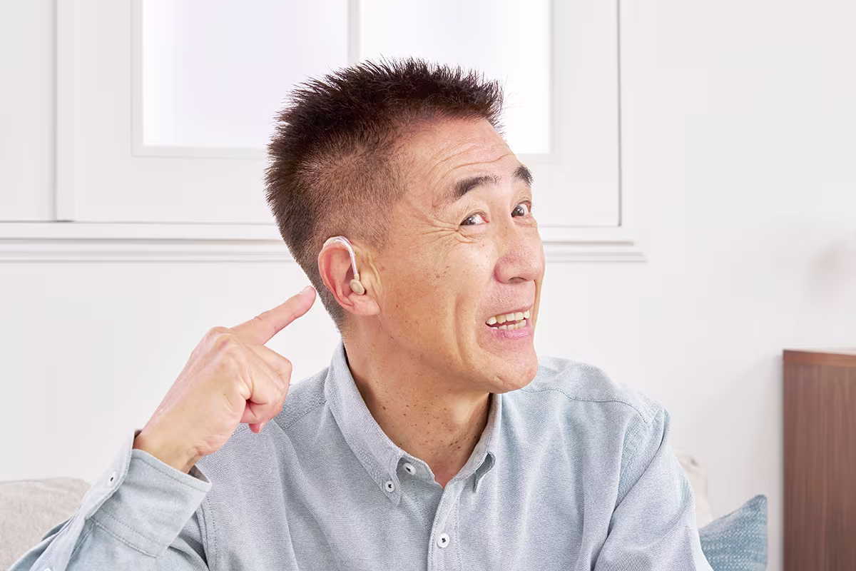 Man pointing to hearing aid while learning about hearing aid styles, technologies, and hearing loss solutions