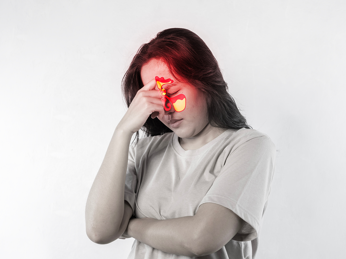 Woman holding her forehead with highlighted sinuses, showing chronic sinus pressure, congestion, and breathing discomfort