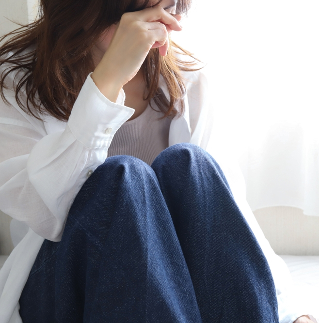 Woman sitting indoors with eyes closed, illustrating how the circadian system regulates sleep and the body’s internal clock.