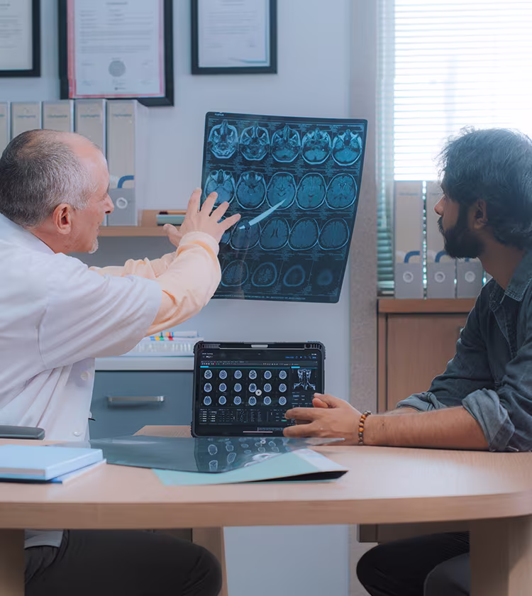 ENT specialist reviewing brain imaging scans with a patient during dizziness and vertigo diagnosis consultation.