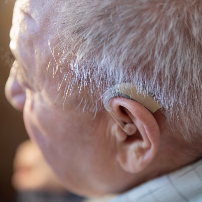 Close-up of older adult wearing a hearing aid during hearing loss evaluation and treatment consultation.