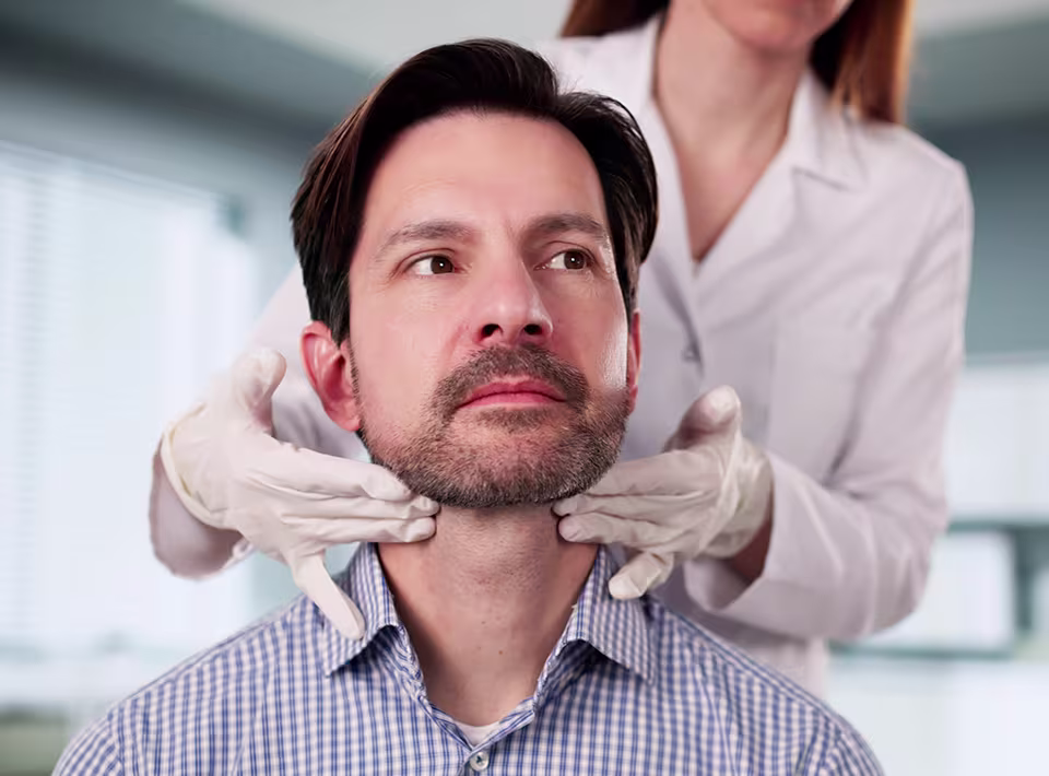 Doctor examining a patient’s neck for a neck mass, swelling, or lump during an ENT evaluation.