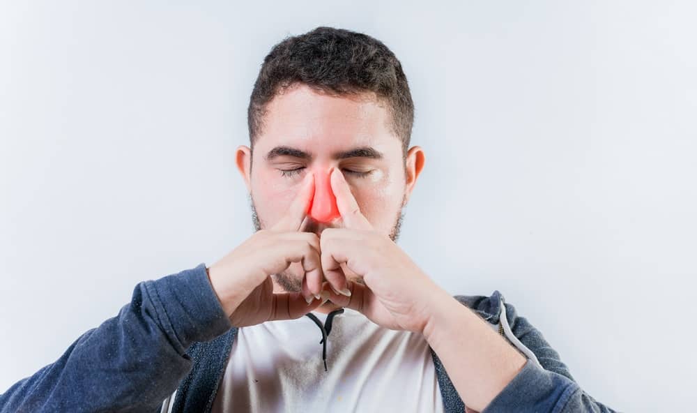 Man experiencing nasal congestion and snoring symptoms linked to sleep apnea and airway obstruction.
