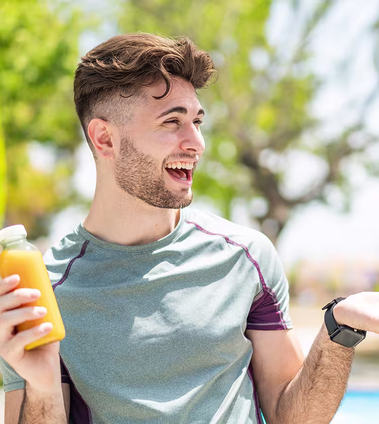 Man holding healthy drink outdoors representing lifestyle changes for improved thyroid health and wellness.