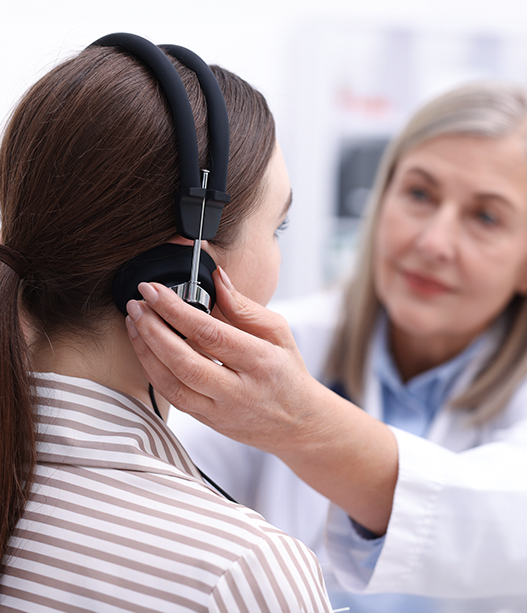 Audiologist performs hearing test for patient receiving ENT ear and hearing care.